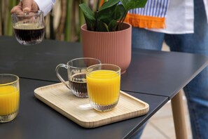 A table with three glasses of orange juice and a mug on a wooden tray. - Korner Montmartre (Paris)