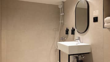 Une salle de bain moderne avec un lavabo blanc, un grand miroir et une douche.