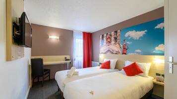 Een hotelkamer met twee bedden, een bureau, een stoel, een televisie en een muurschildering.