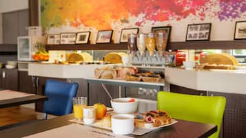 Un desayuno servido en una mesa, sillas y mostrador con diferentes alimentos y bebidas.
