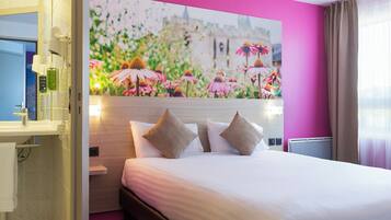 A hotel room with a bed, a nightstand, a mirror, and a wall with a floral painting.