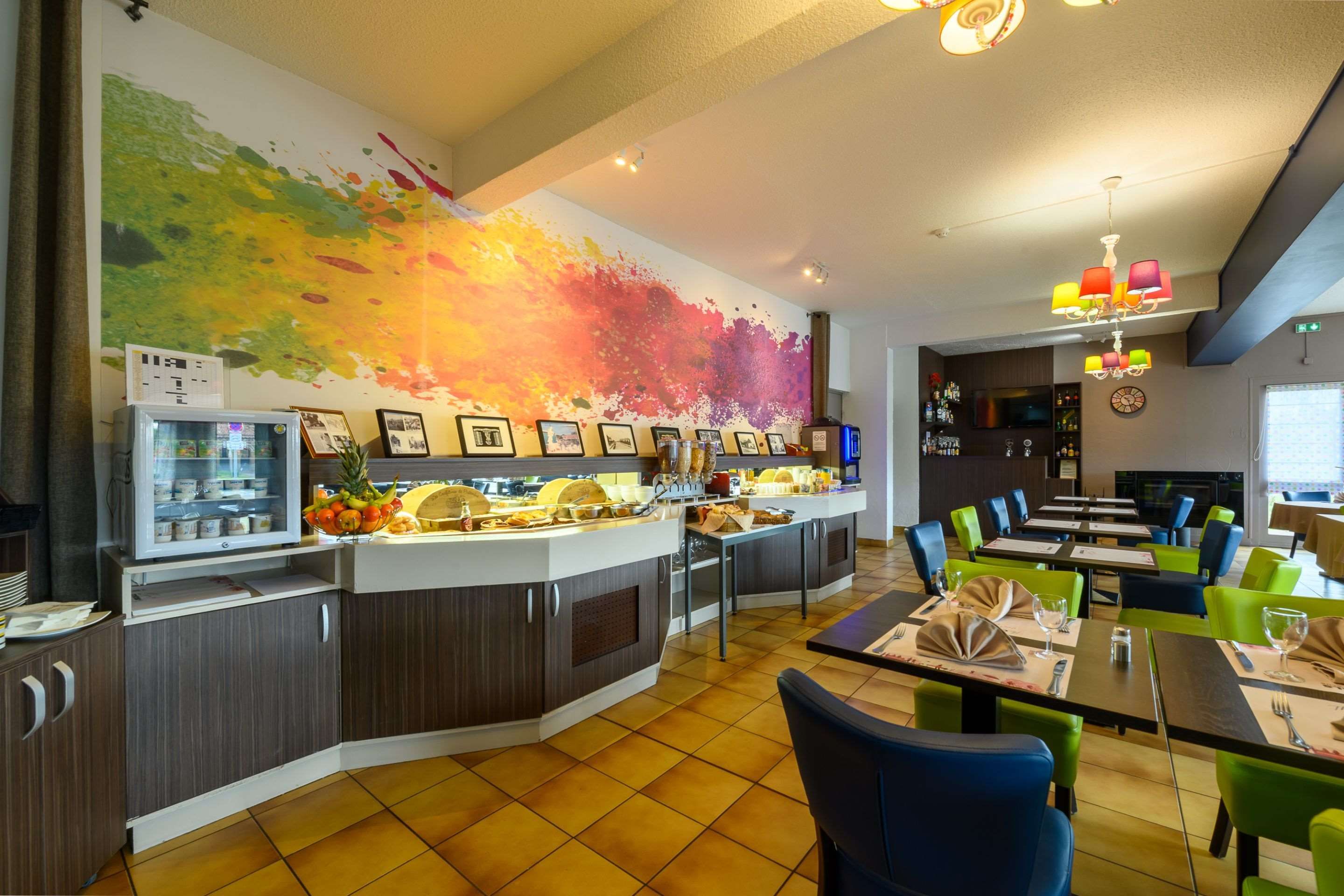 Un restaurante con un mural colorido, una barra de buffet y un mobiliario moderno.