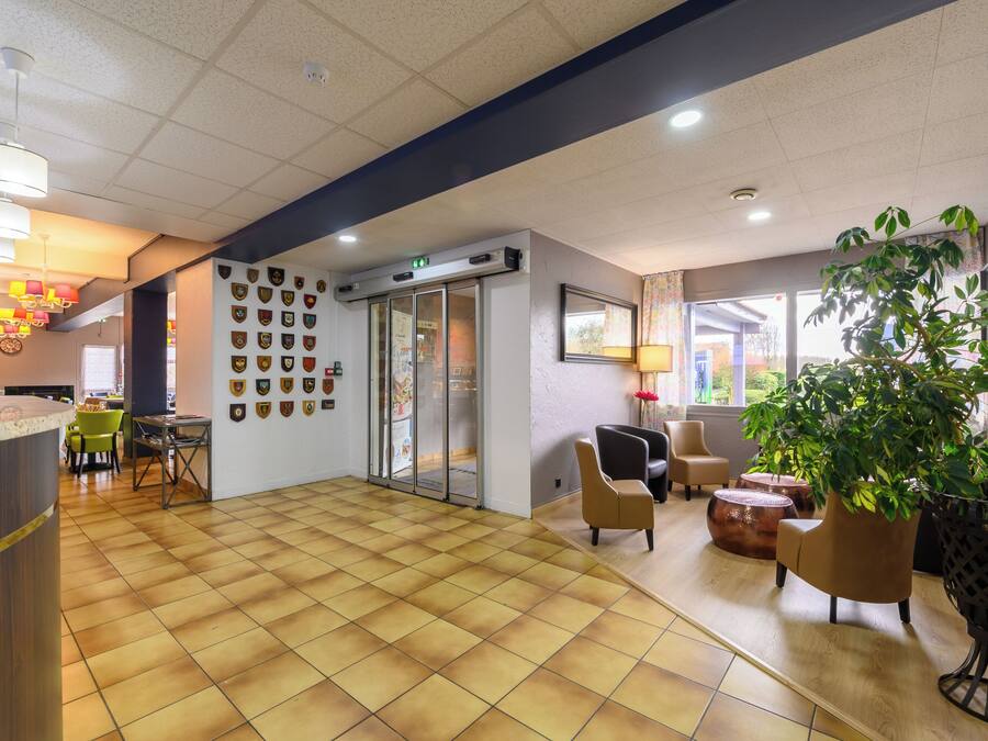 A reception area with a check-in counter, a wall of badges, a seating area with chairs, and a large potted plant.