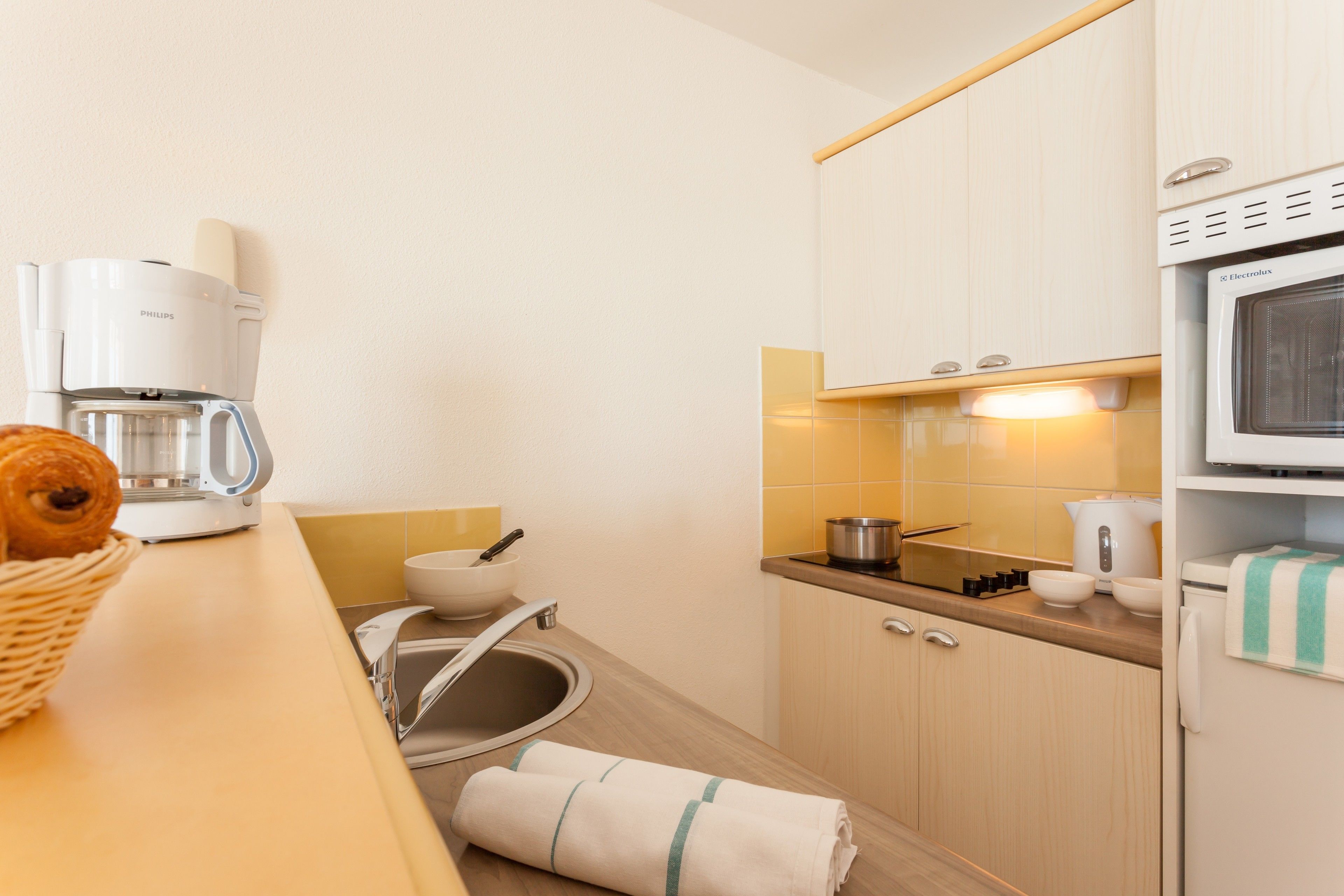 A modern kitchen with a coffee maker, a microwave, and a sink.