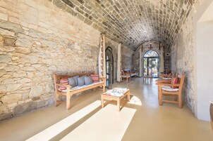 Interior con paredes de piedra, un banco de madera, una mesa de centro y una zona de comedor con sillas.