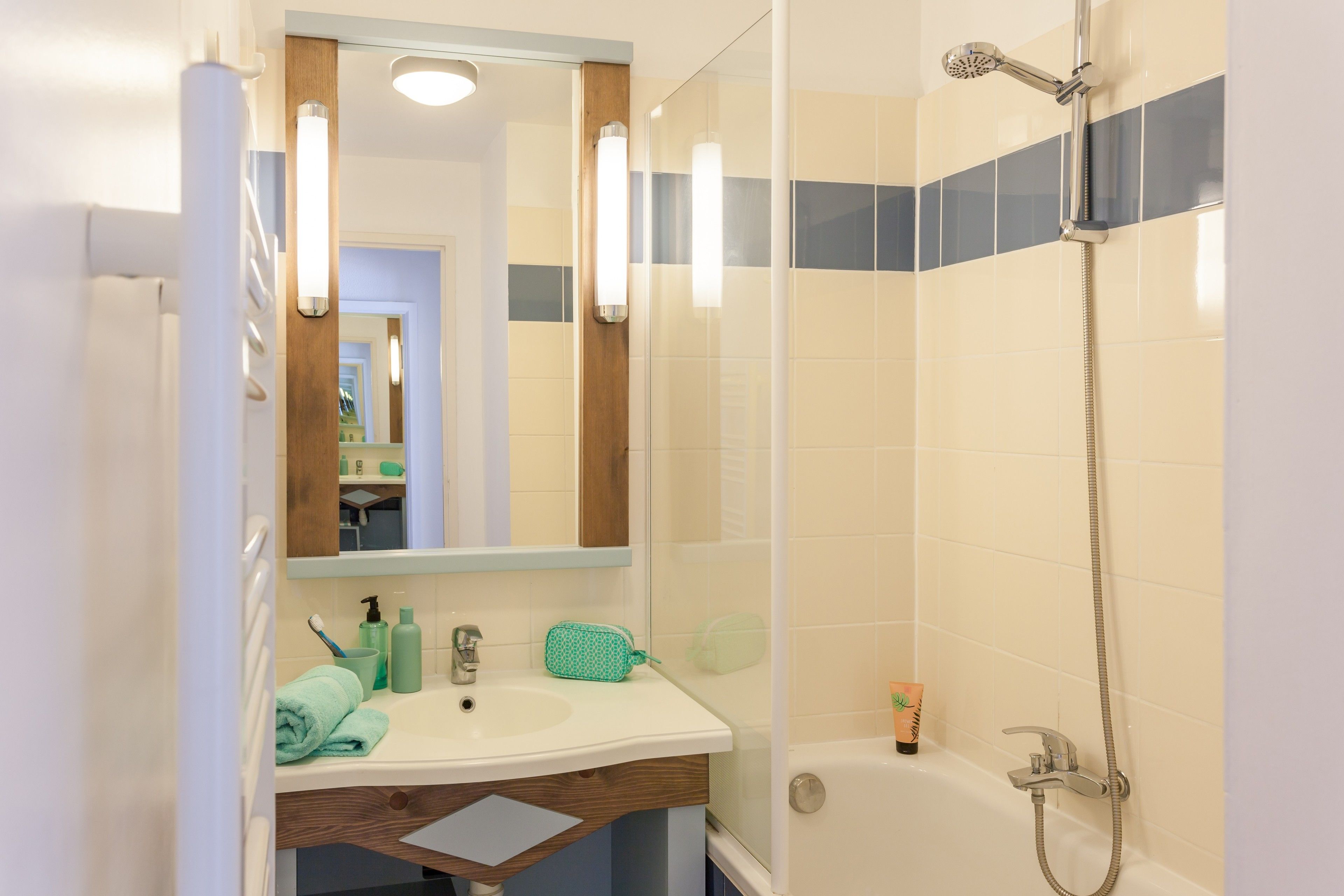 A bathroom with a sink, mirror, and shower.