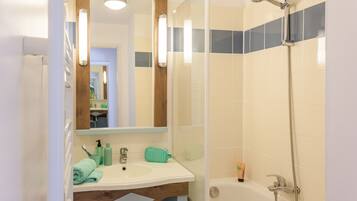A bathroom with a sink, mirror, and shower.
