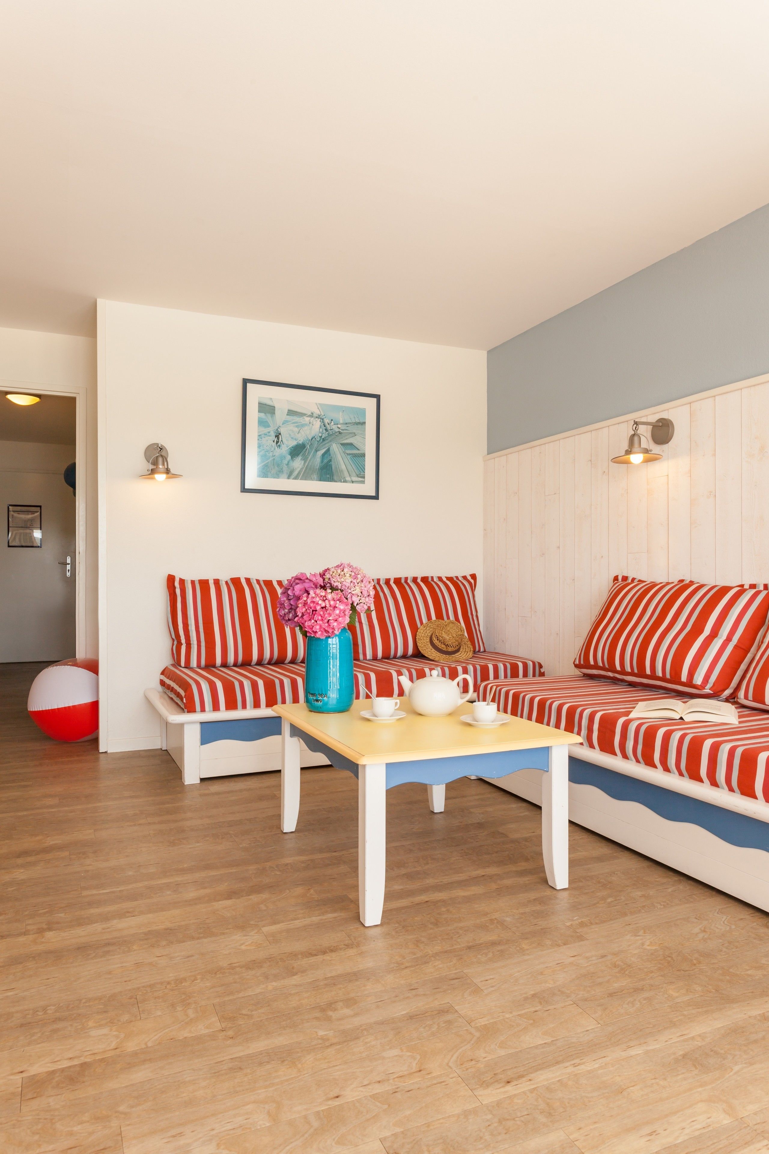 A cozy living room with striped sofas, a wooden coffee table, and a beach ball.