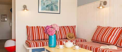 A cozy living room with striped sofas, a wooden coffee table, and a beach ball.