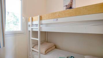 A bunk bed room with a window, a picture on the upper bunk, and a pair of headphones on the lower bunk.