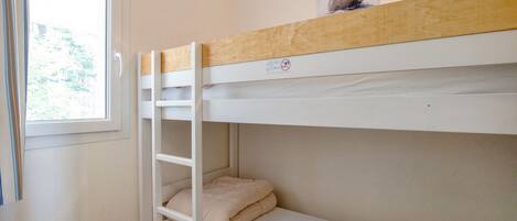 A bunk bed room with a window, a picture on the upper bunk, and a pair of headphones on the lower bunk.