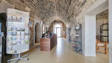 A spacious lobby with a high arched brick ceiling, a reception desk, and a display of postcards.