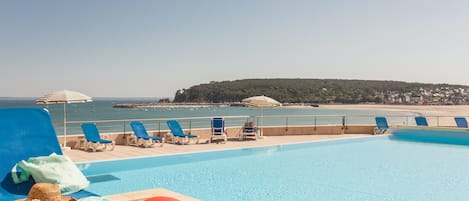 Una piscina al aire libre de temporada, sombrillas, tumbonas