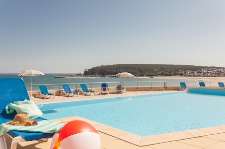 Una piscina al aire libre de temporada, sombrillas