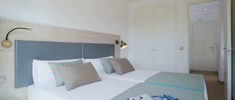 Un lit bien fait, avec une couvre-lit à rayures, une lampe de chevet et un magazine posé sur le lit.