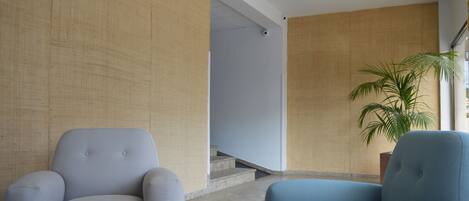 A modern lobby with two armchairs, a staircase, and a potted plant.