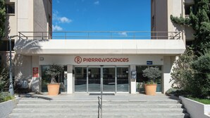 L’entrée d’un hôtel, avec une enseigne indiquant « PIERRE&VACANCES » et une autre indiquant « Playia 1 ».