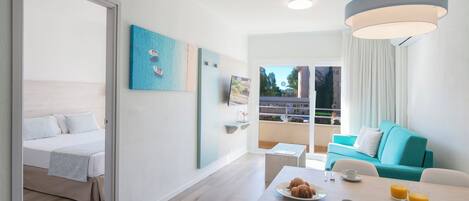 Une chambre d’hôtel moderne comprenant un lit, un coin repas avec petit-déjeuner, un balcon avec vue et un mur d’accent bleu.