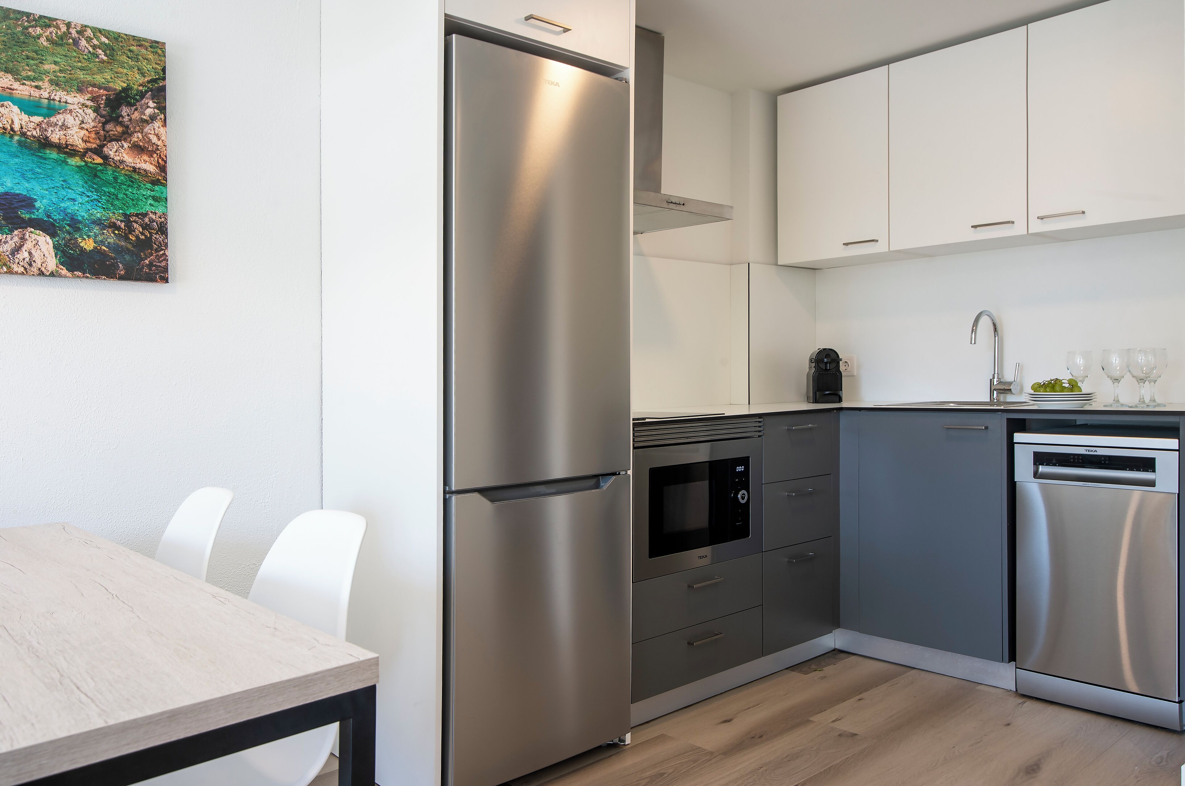 Una cocina moderna con electrodomésticos de acero inoxidable, lavavajillas y un comedor con mesa y sillas.