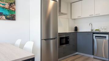 Una cocina moderna con electrodomésticos de acero inoxidable, lavavajillas y un comedor con mesa y sillas.