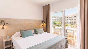 A hotel room with a bed, bedside tables, a lamp, and a view of the outside balcony.