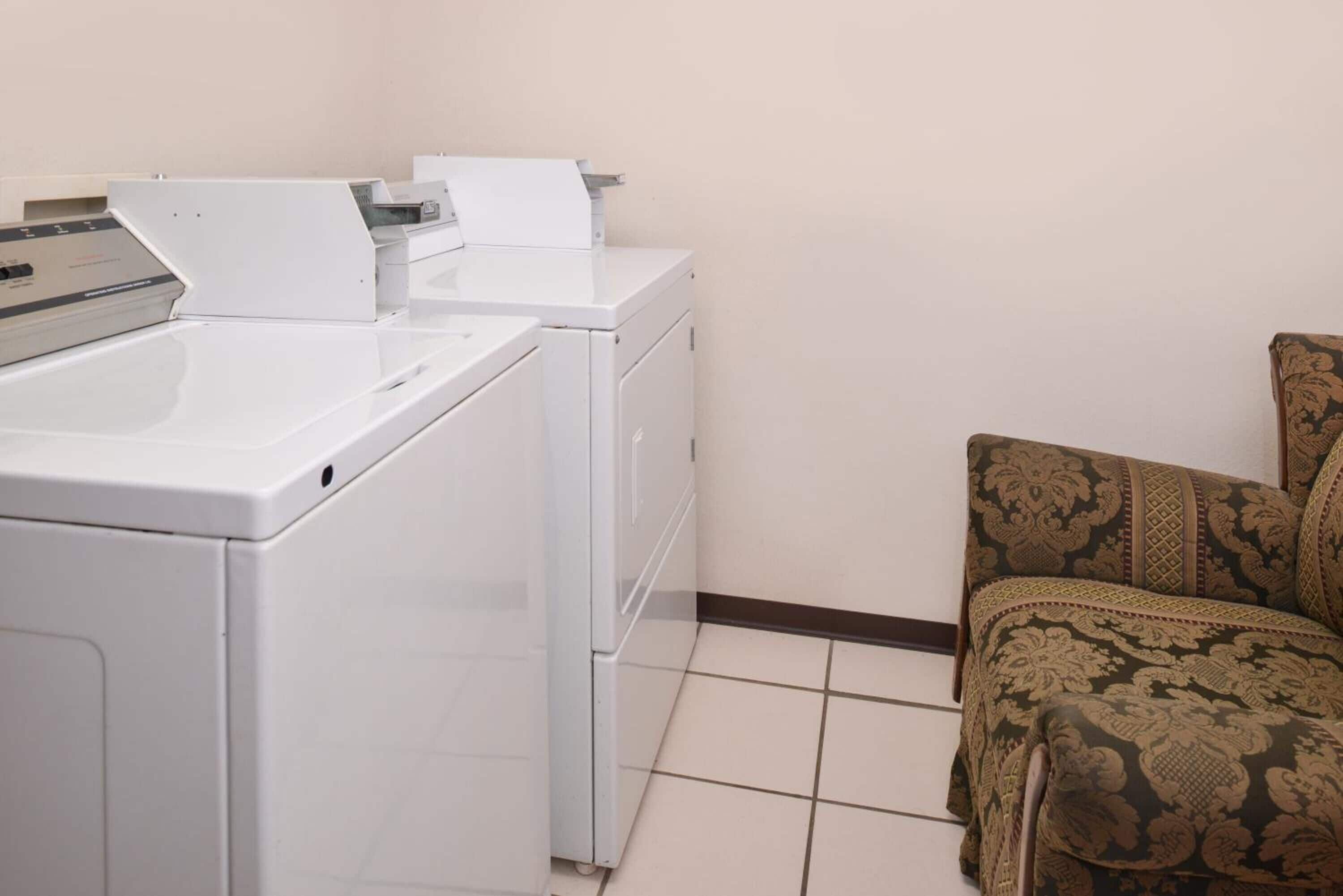 Un angolo lavanderia con due lavatrici bianche e un divano decorato.