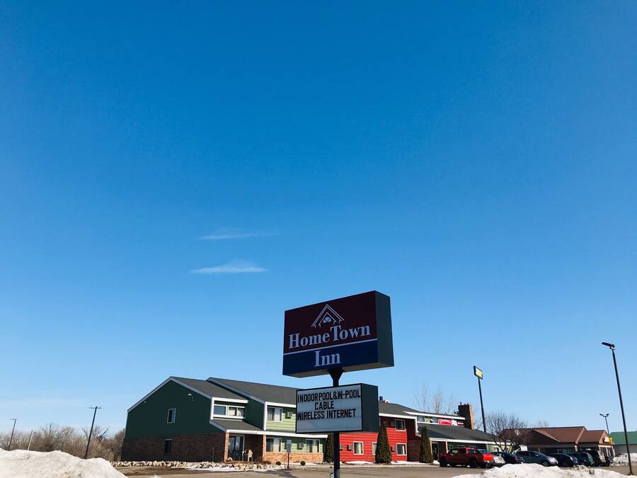 Un edificio con el cartel de HomeTown Inn, que ofrece comodidades como piscina cubierta, Wi-Fi e internet por cable.