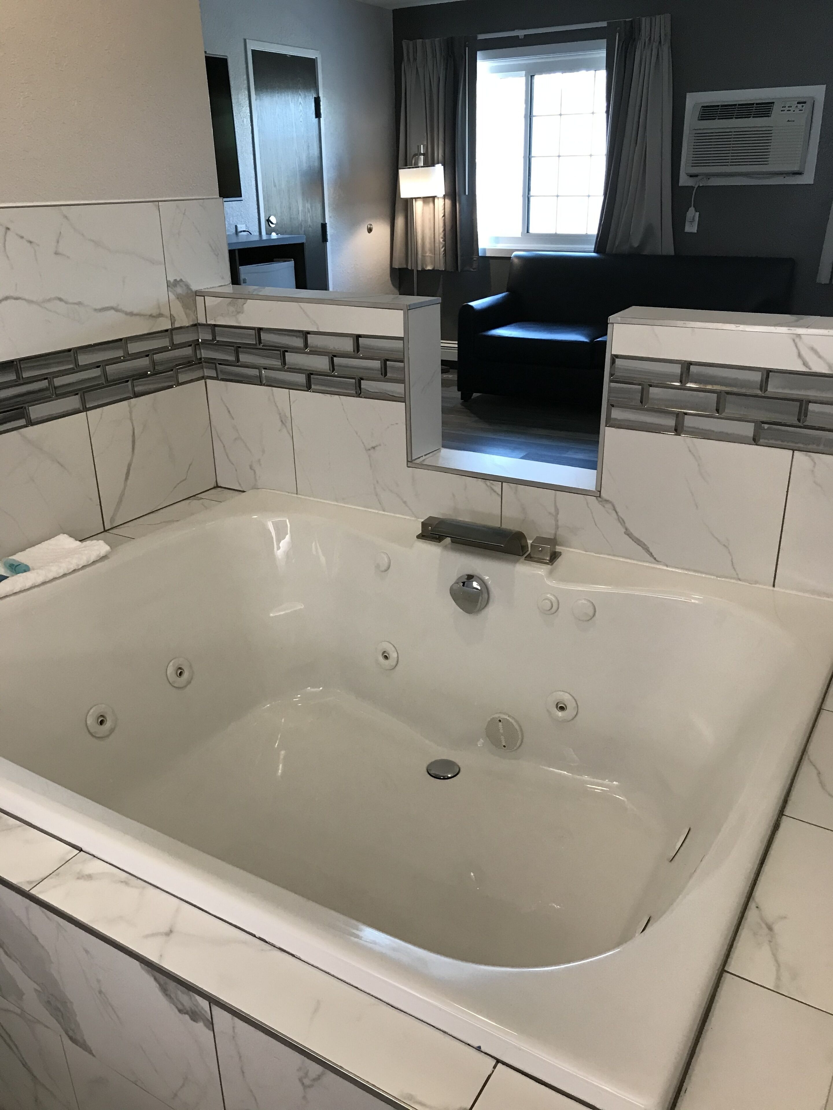 Un baño moderno con una bañera grande, baldosas de mármol y un banco empotrado.