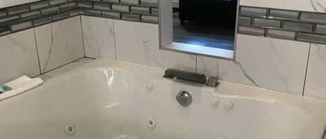 Une salle de bain moderne avec une grande baignoire, des carreaux de marbre et un banc intégré.