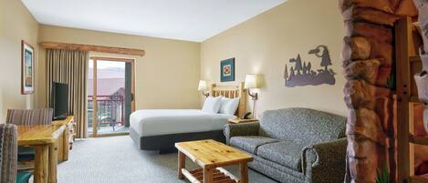 A hotel room with a bed, a sofa, a wooden coffee table, a TV, and a balcony with curtains.