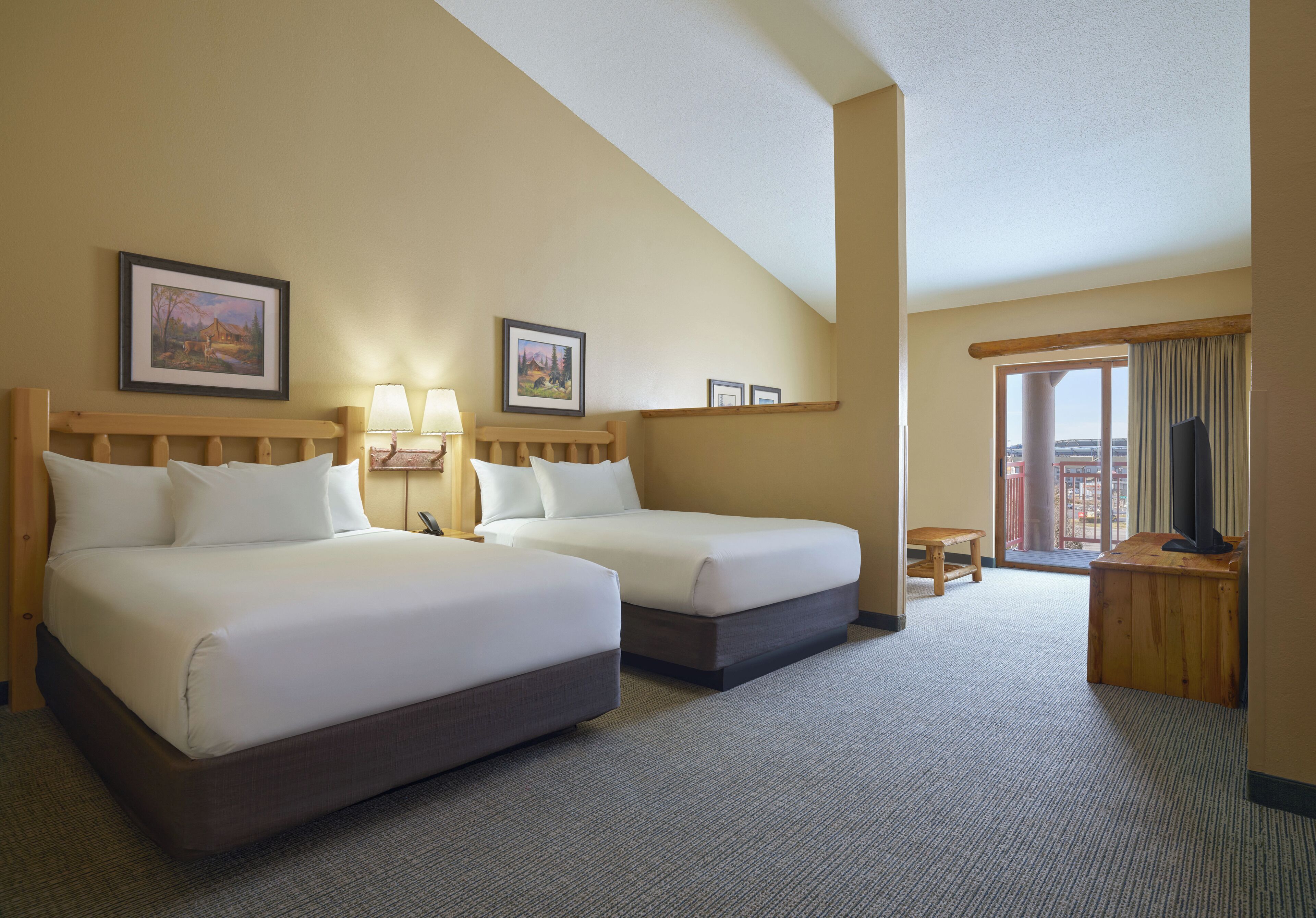 A hotel room with two beds, a television, a small table, and a window with curtains.