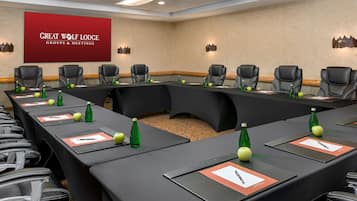 A conference room with a long table, multiple chairs, and a projector screen displaying "GREAT WOLF LODGE GROUPS & MEETINGS".