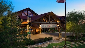 A lodge with a prominent American flag, a large entrance with a sign reading "Great Wolf Lodge," and a well-maintained front yard with a wooden fence.