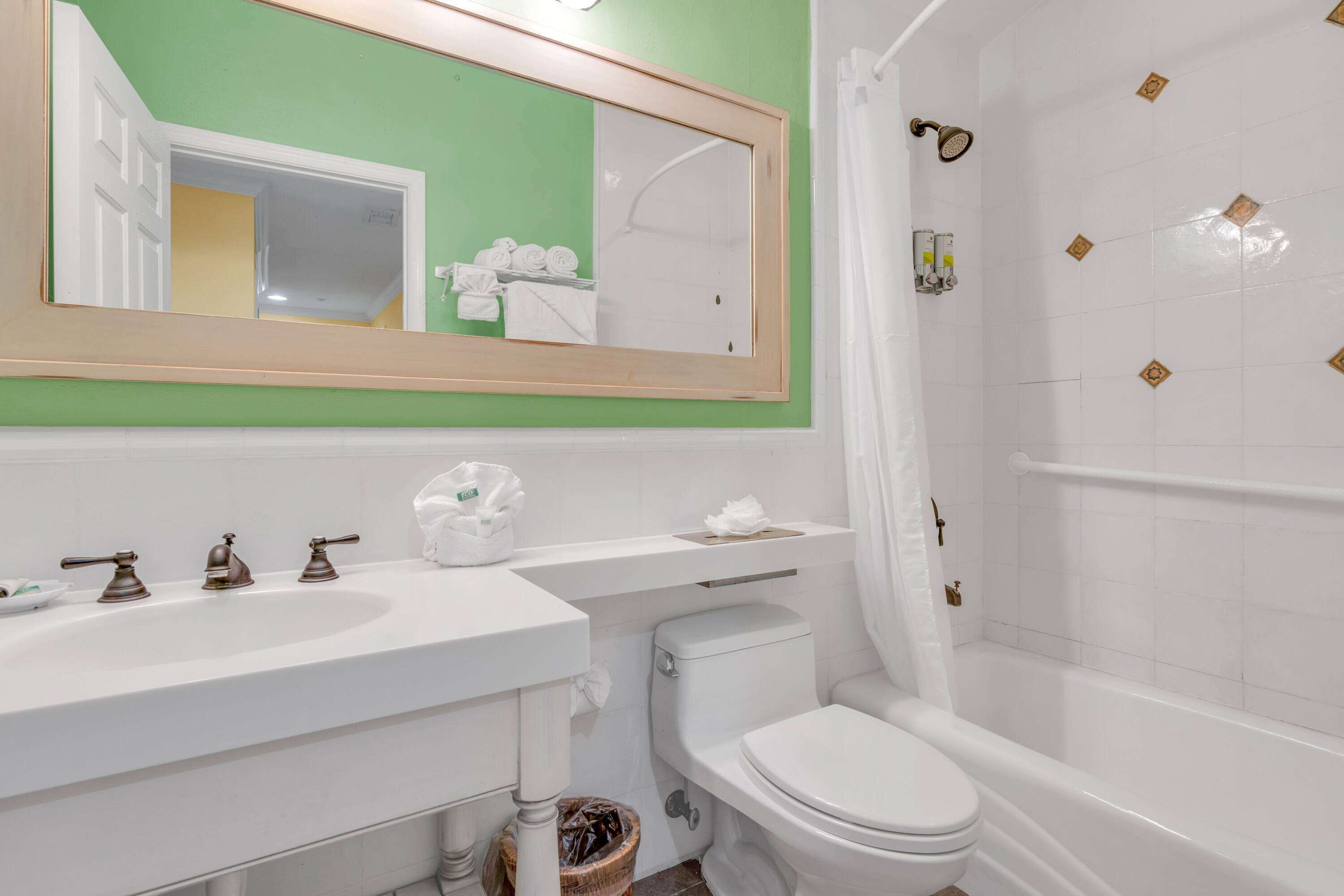 A bathroom with a white sink, two faucets, a toilet, and a bathtub with a shower curtain.