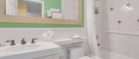 A bathroom with a white sink, two faucets, a toilet, and a bathtub with a shower curtain.