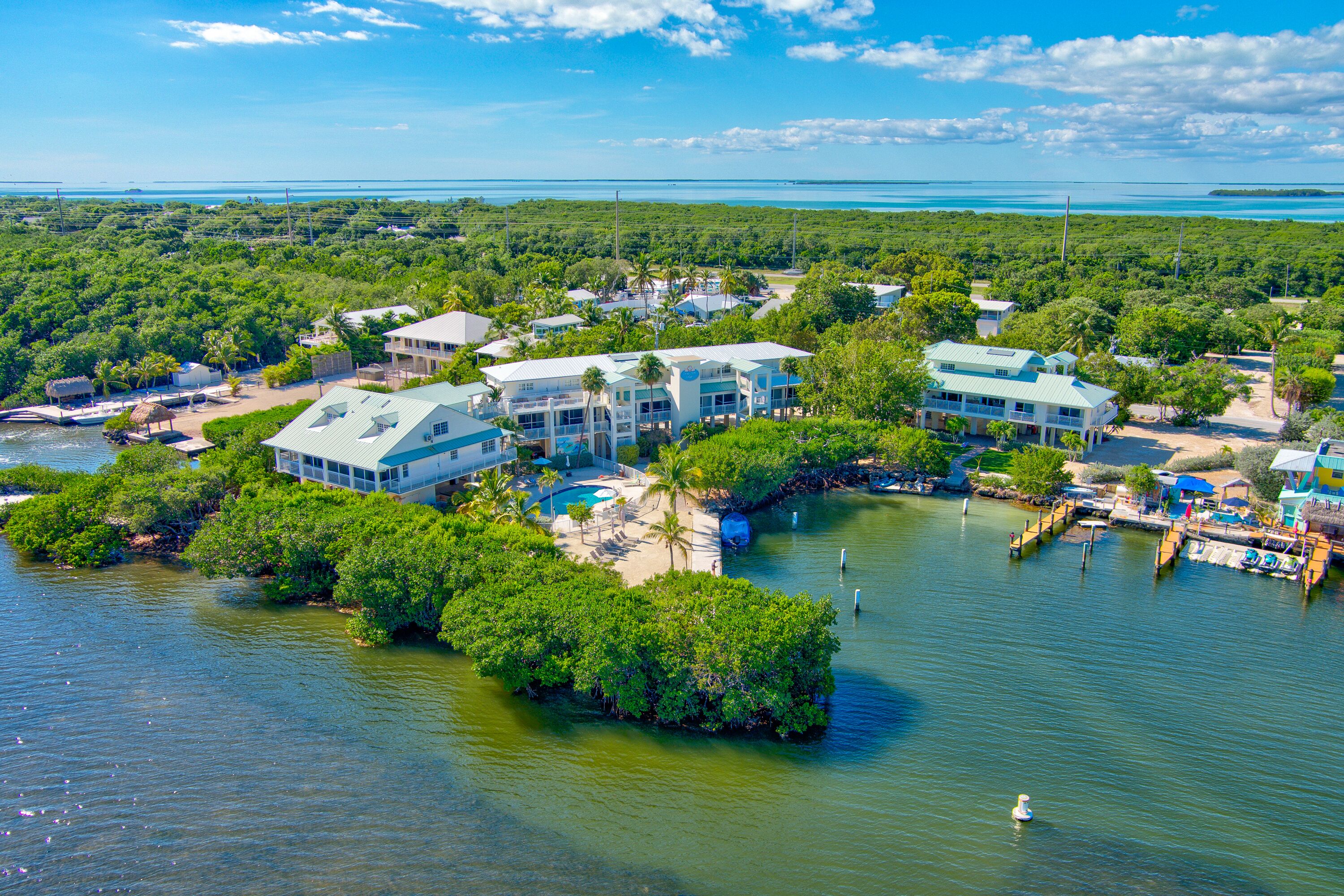 A coastal resort with multiple buildings, a swimming pool, and a dock area.