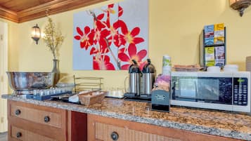 Une cuisine dotée d’un plan de travail en granit, d’une machine à café, d’un four à micro-ondes et d’un luminaire fixé au mur.