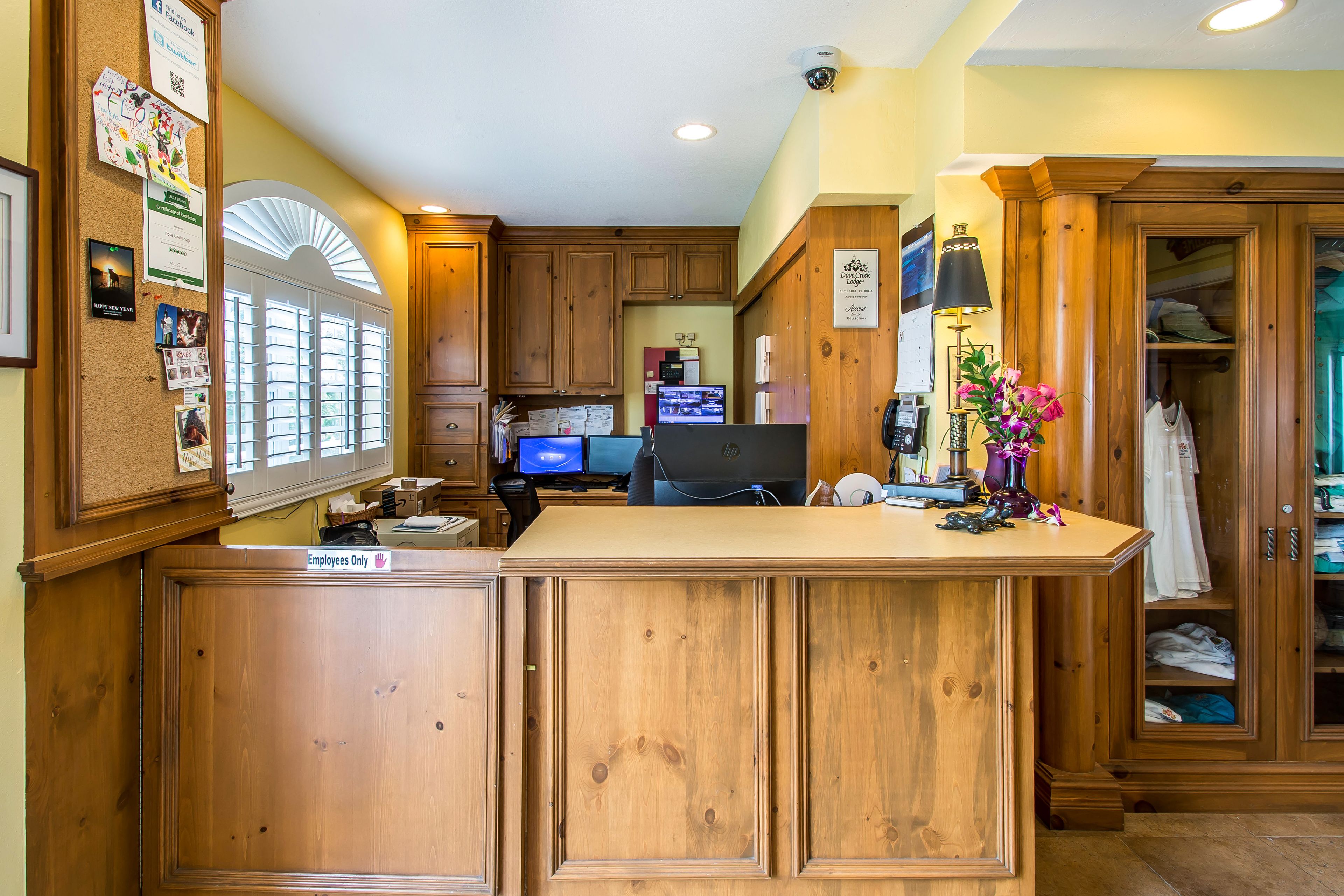 A kitchen with wooden cabinets, a computer, and a refrigerator.