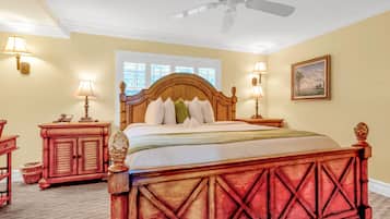 A bedroom with a wooden bed, two bedside tables with lamps, a ceiling fan, and a window with blinds.