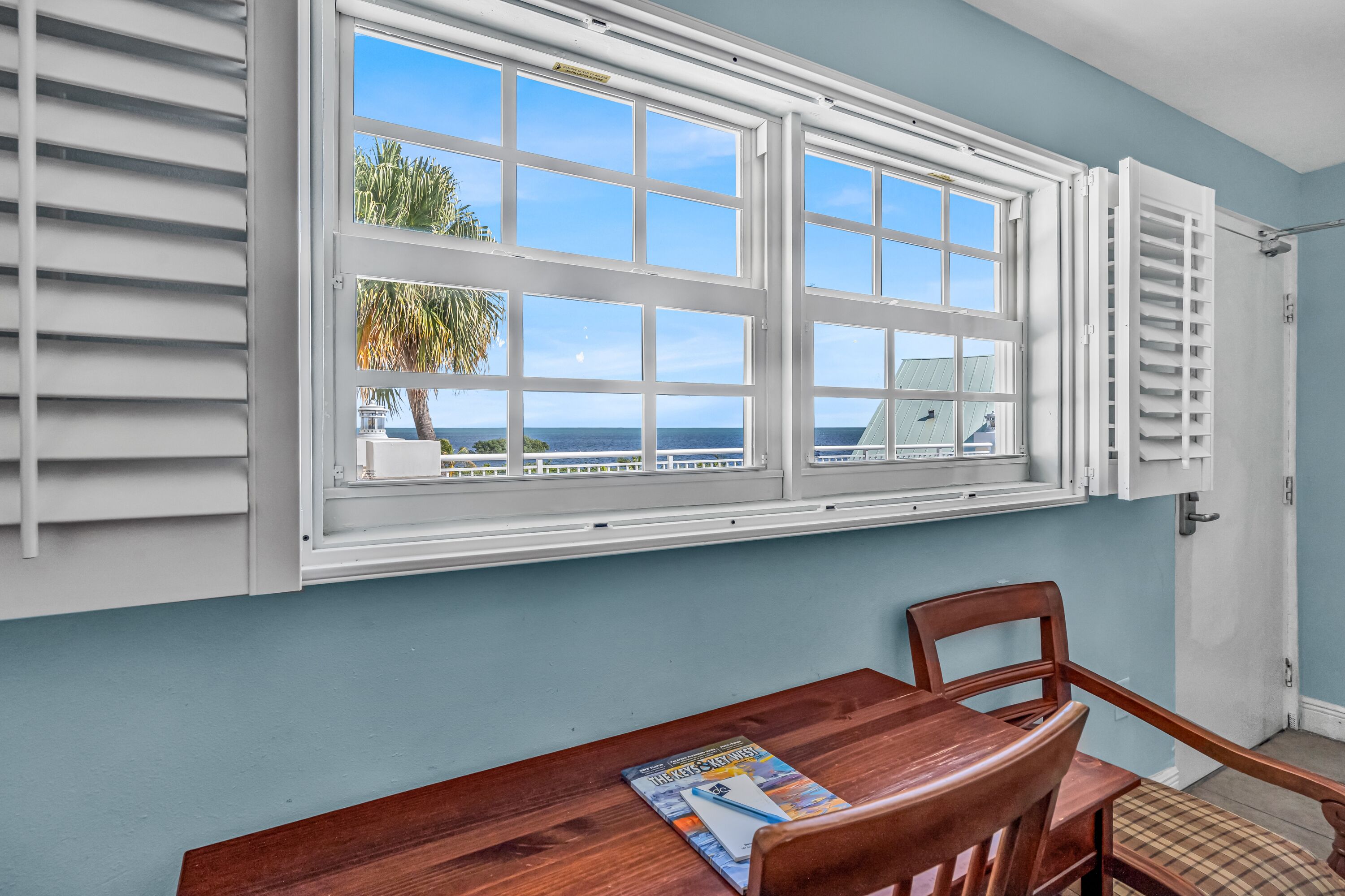 A room with a large window, a wooden table, and a chair.