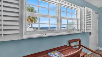 A room with a large window, a wooden table, and a chair.