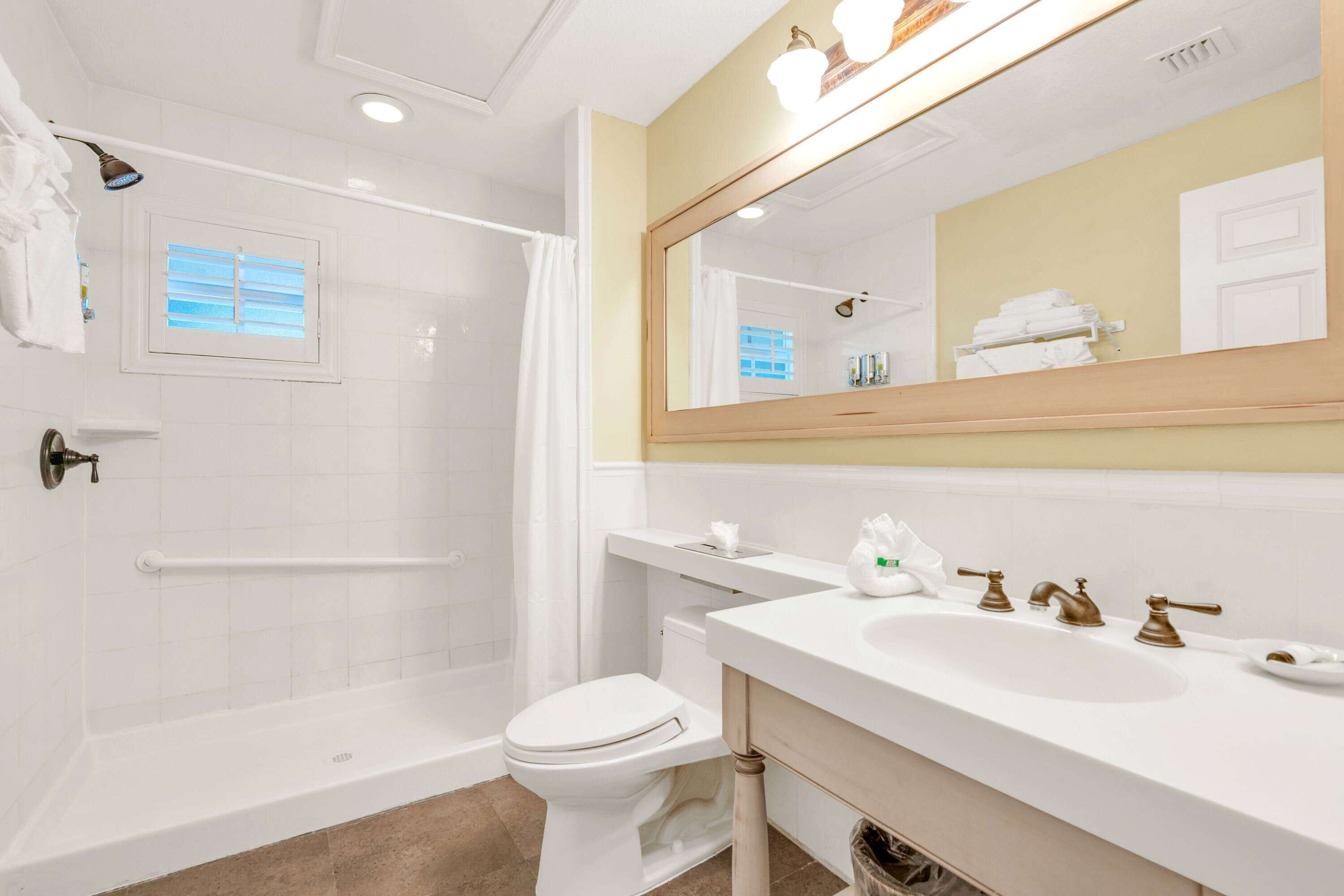 A bathroom with a bathtub, toilet, sink, and a large mirror.