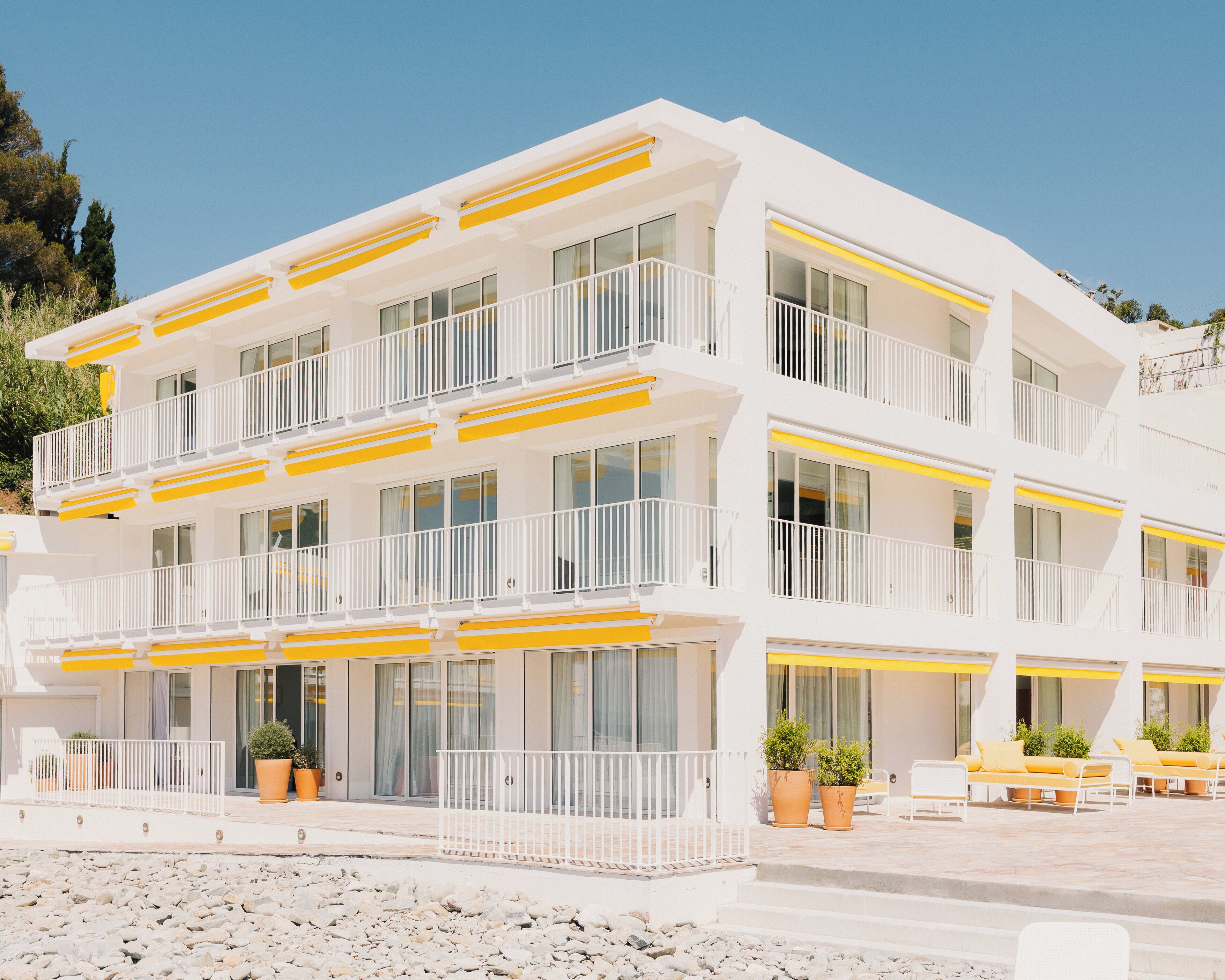 A multi-story hotel with balconies, large windows, and outdoor seating areas.