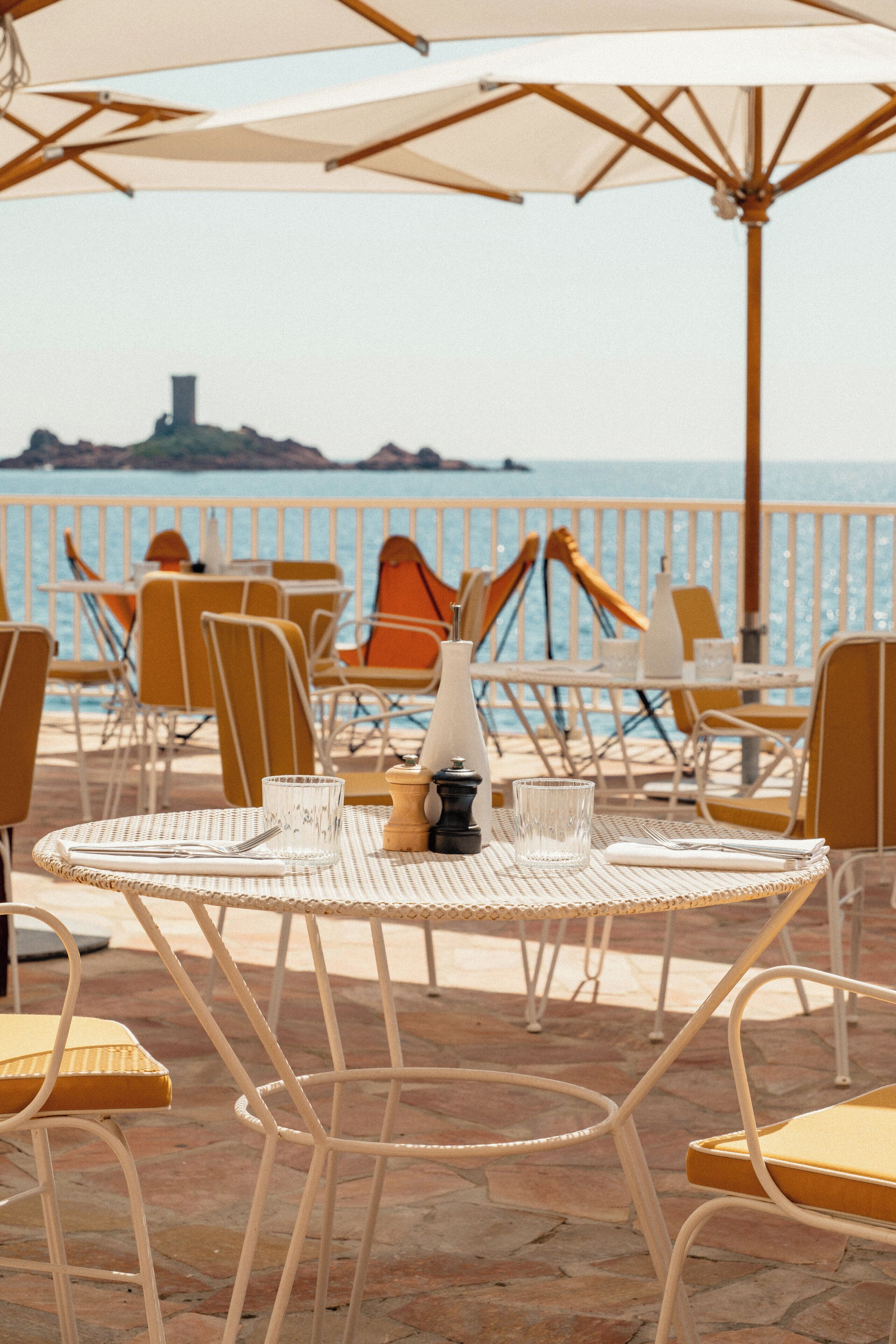 En restaurant ved havet med udendørs siddepladser, borde og stole med udsigt over havet.