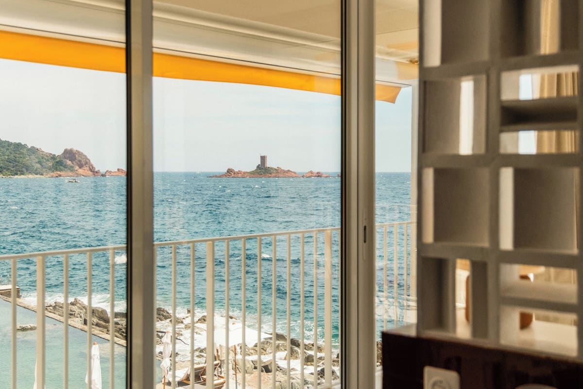 Uma varanda com vista para o mar e uma ilha distante com uma torre.