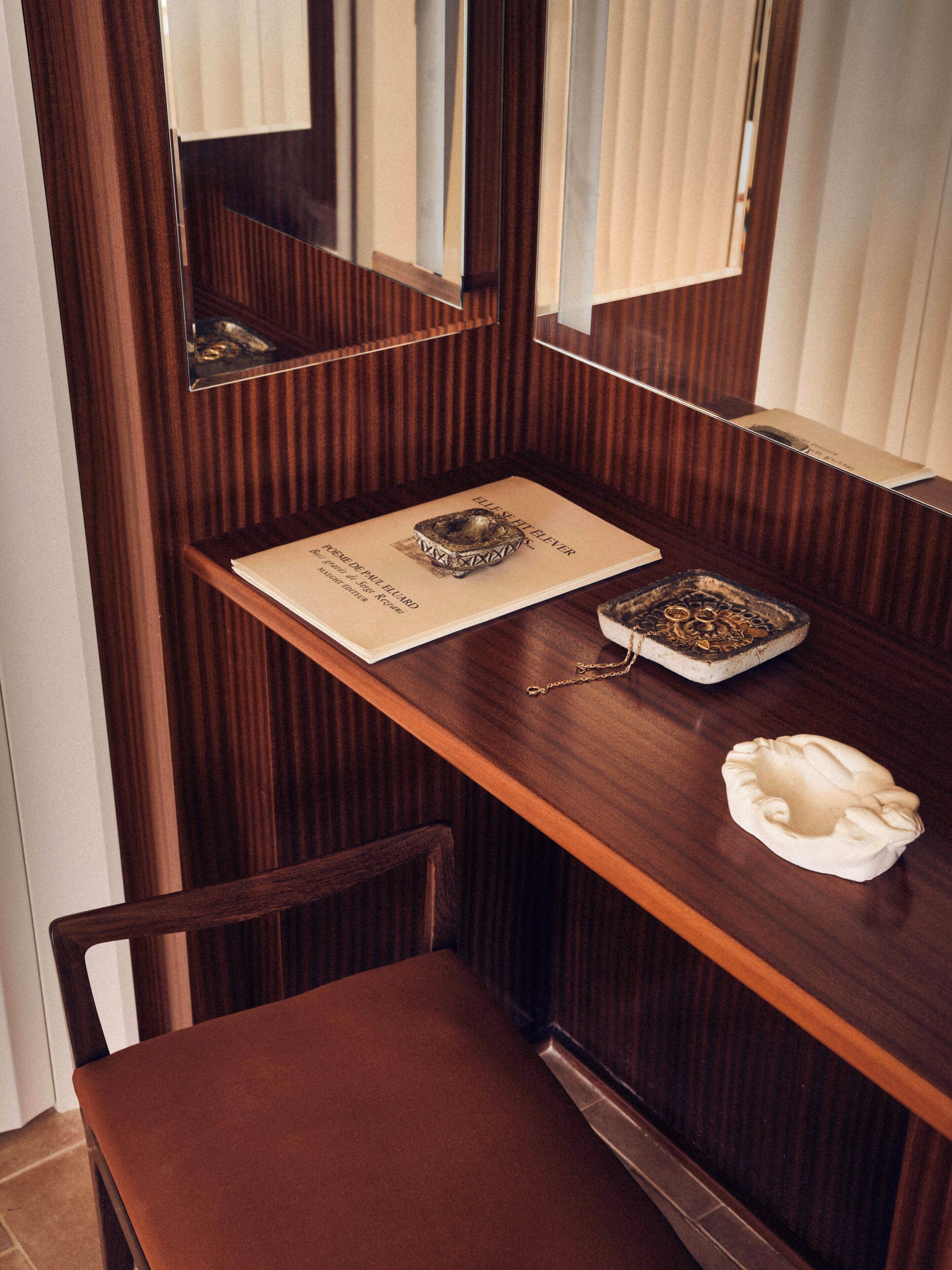 A wooden desk with a mirror, a framed menu, and a small ashtray.