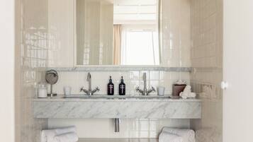 Une salle de bain avec un lavabo en marbre, deux robinets, un miroir et deux porte-serviettes.
