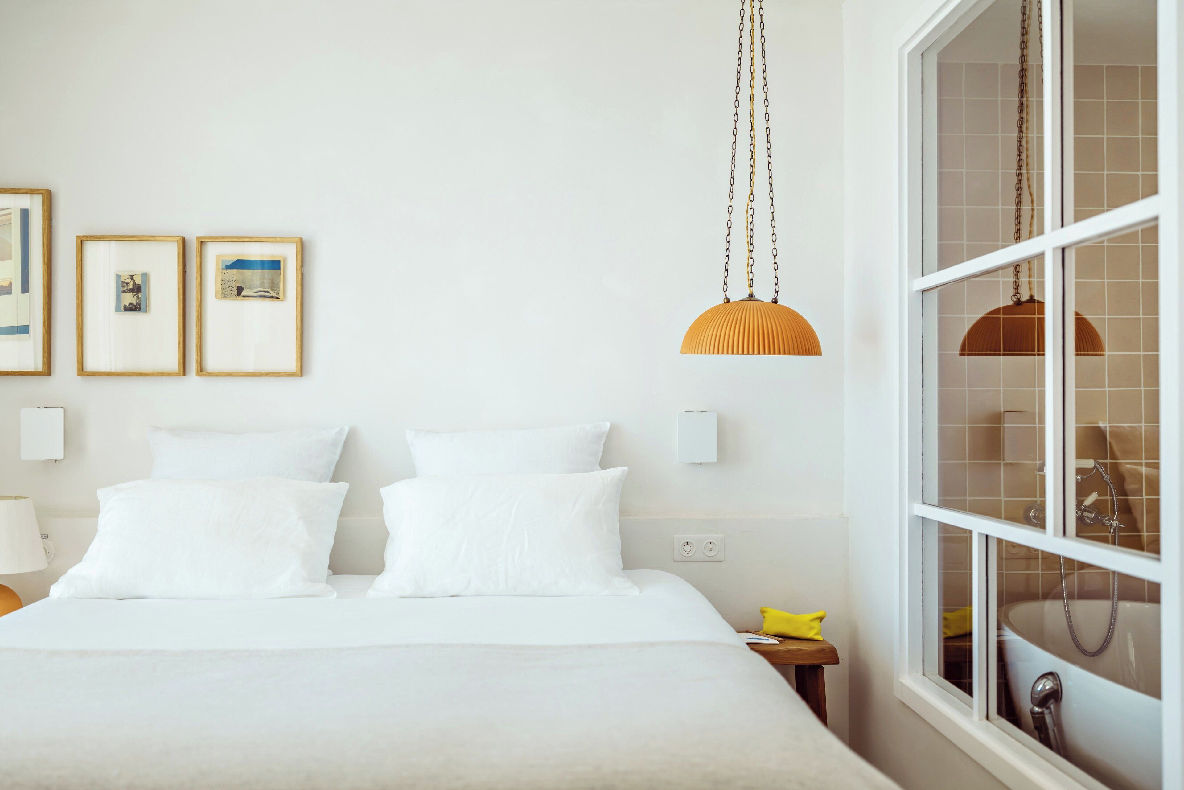 Une chambre à coucher bien rangée, avec un lit, une table de chevet et une fenêtre donnant sur une salle de bain.
