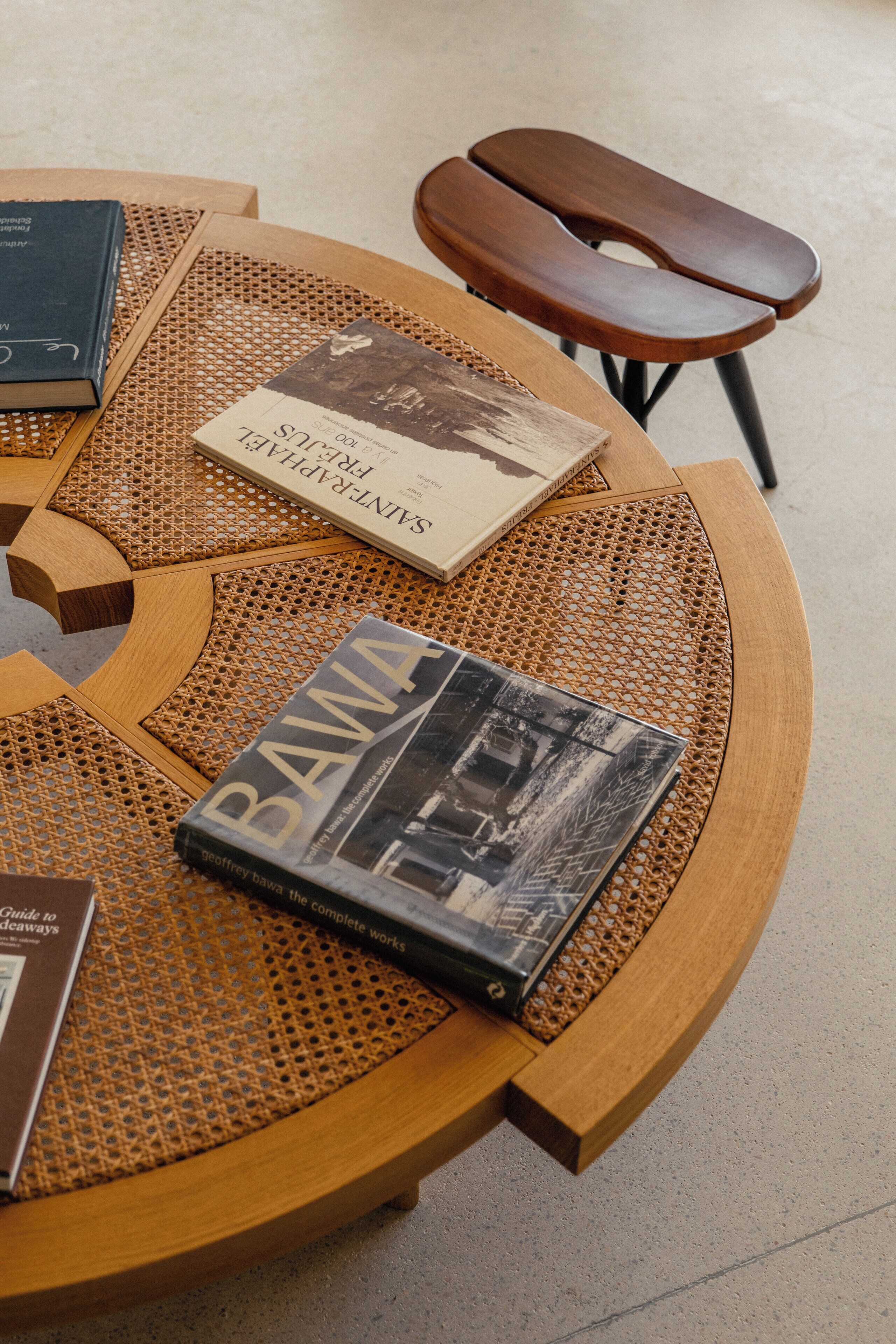 A round wooden table with a woven surface, accompanied by a bench.