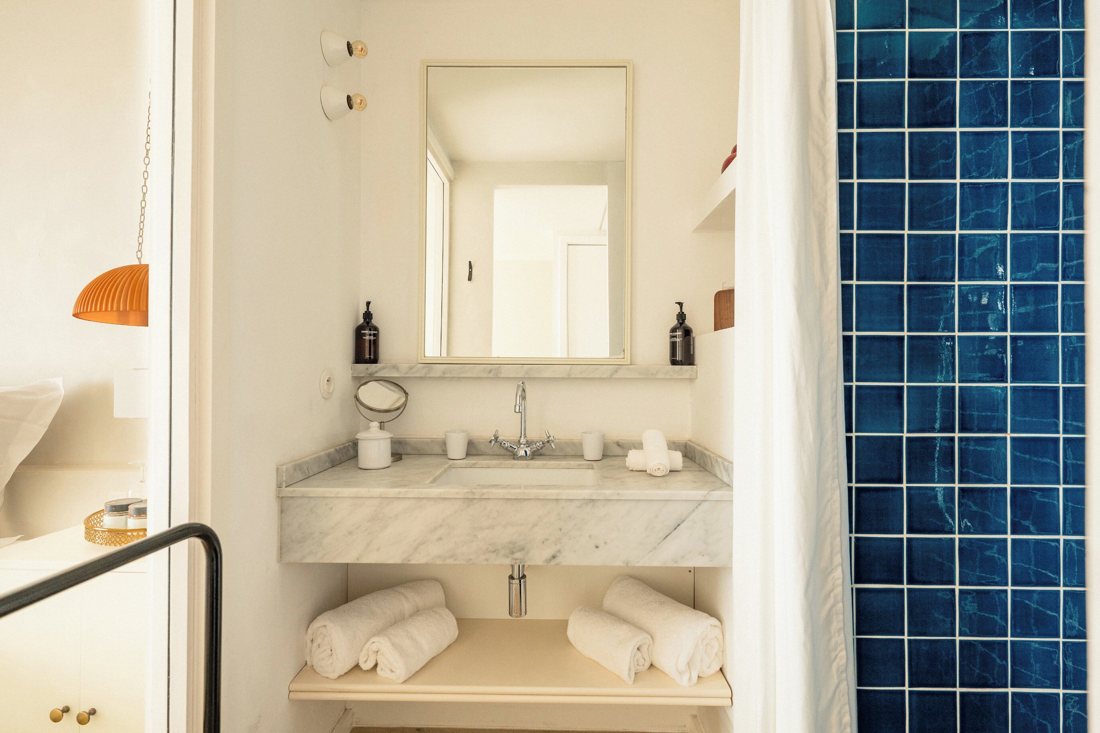 A bathroom with a marble sink, a mirror, and a blue-tiled wall.